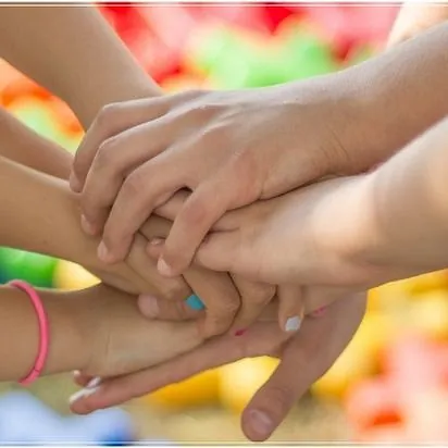 Mehrere Hände übereinander gestapelt als Zeichen der Einheit.