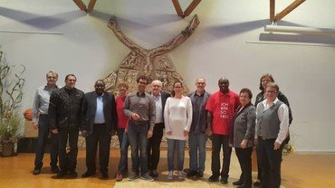 Gruppe Menschen vor Wandskulptur.