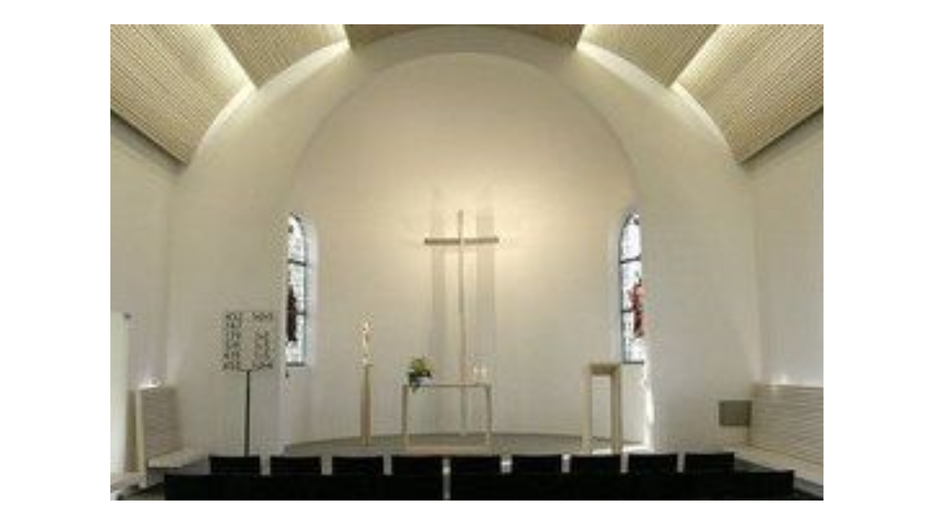 Minimalistischer Kirchenraum mit Altar und Kreuz.