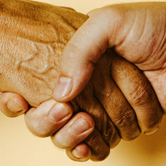 Ältere Hände halten sich gegenseitig fest.