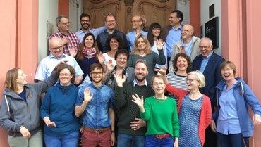 Gruppe von Personen winkt in die Kamera.